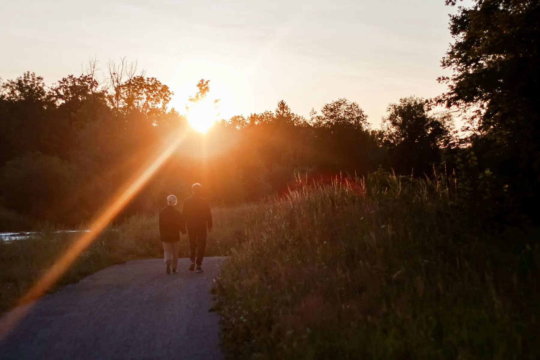 An older couple walking together along a path at sunset